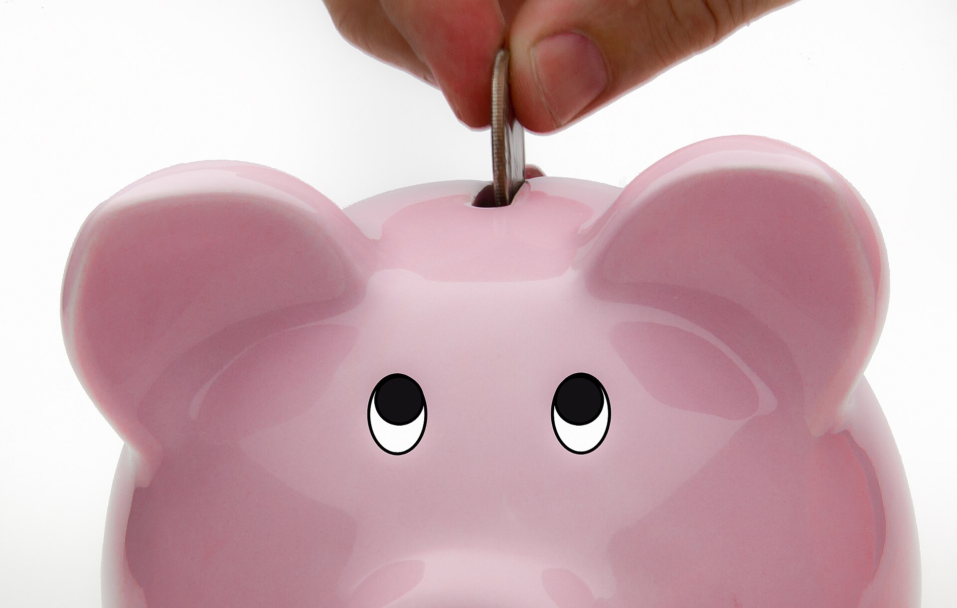 Coins being deposited into a piggy bank