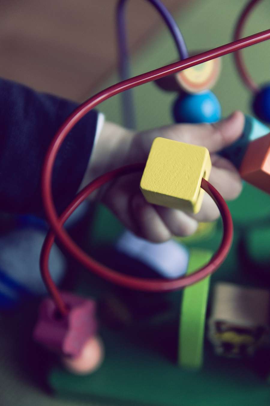 A toddler playing with a bead toy at home
