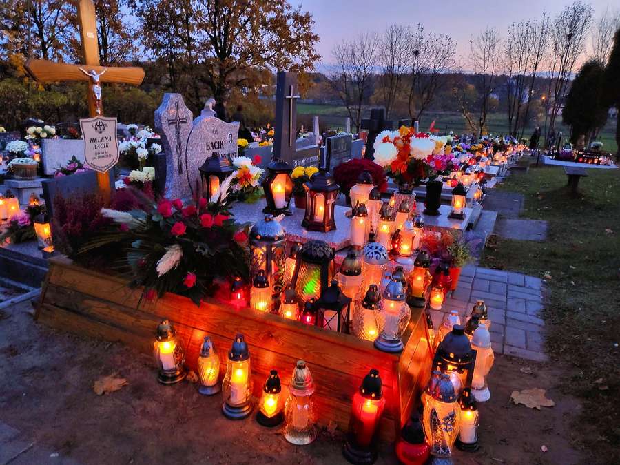 A grave covered in znicze lanterns at dusk - one candle is always a welcome gesture