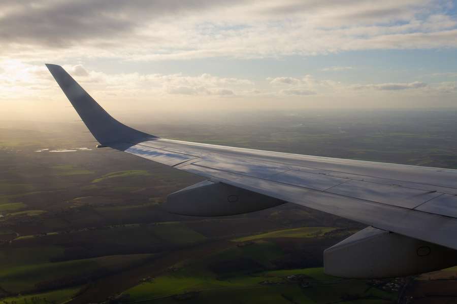 An Embraer 190 winglet against a sunset sky above the clouds
