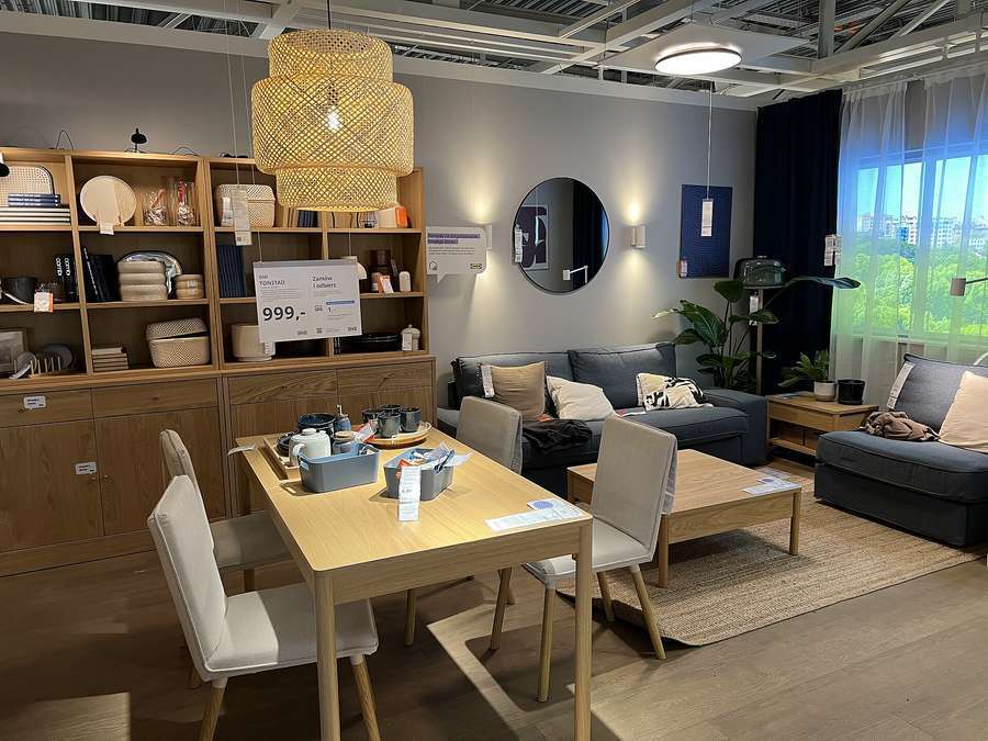 A living room and dining furniture display in a Polish store with a 999 zloty price tag