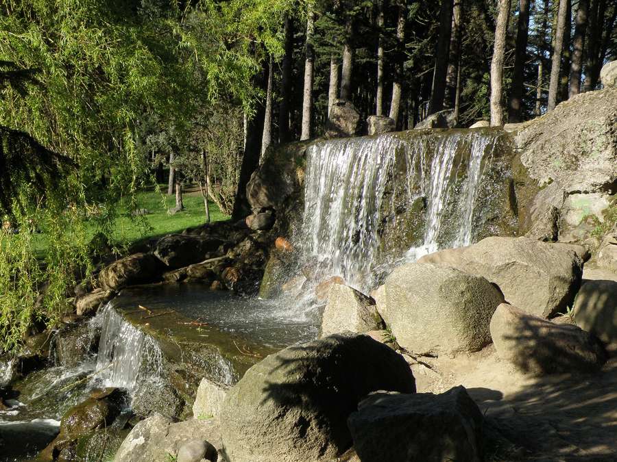 Waterfall over rocks among trees in Skaryszewski Park, Warsaw
