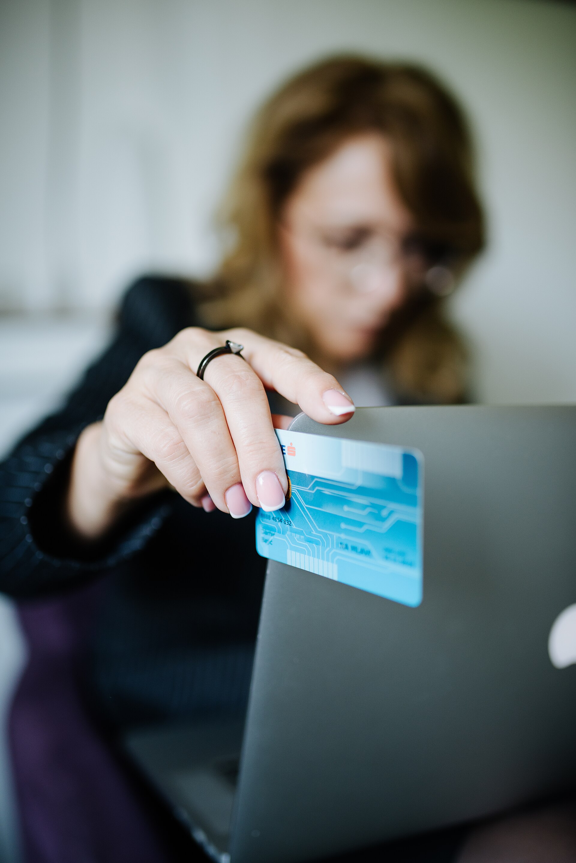 A shopper holding a credit card at a laptop while buying online