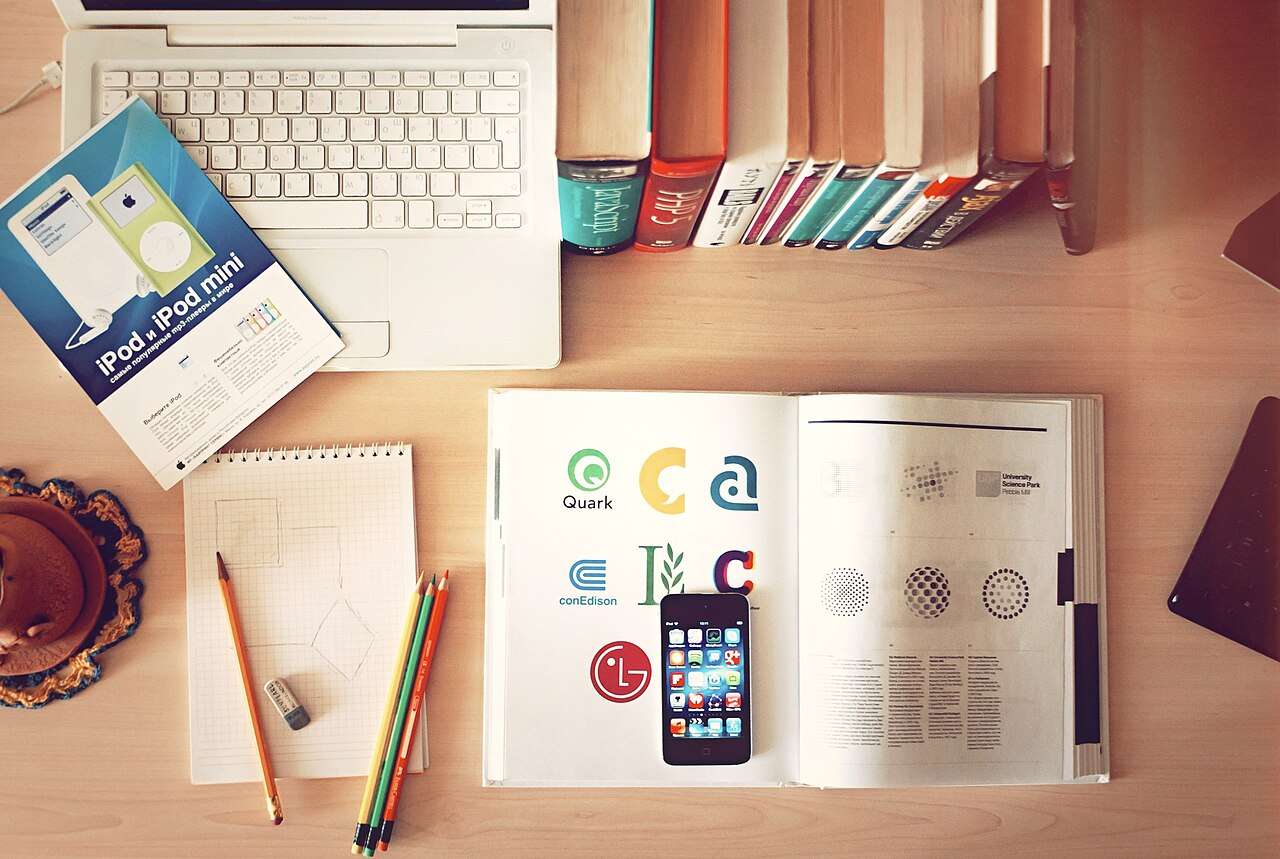 A laptop, books and a phone on a desk