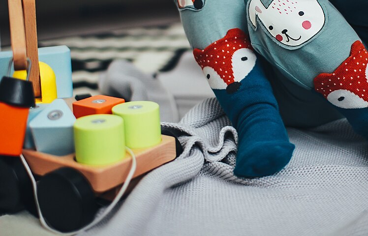 A child's hands reach for a stethoscope and thermometer on a table - registering your child activates their NFZ cover