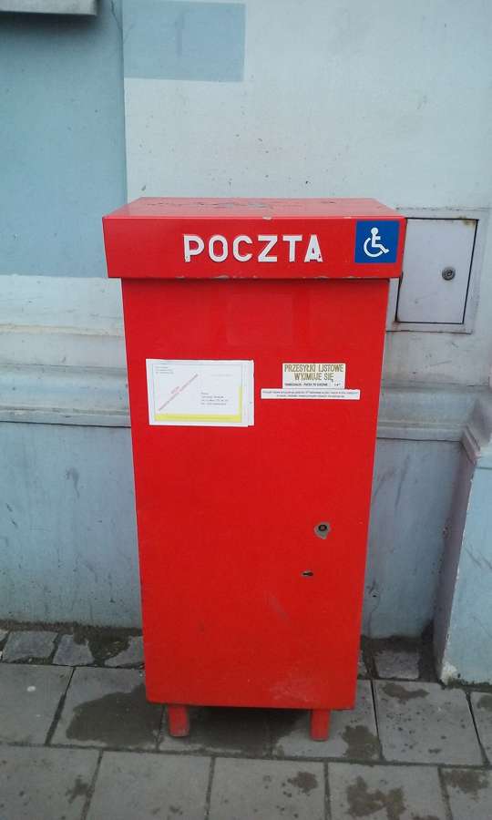A red Poczta Polska post box on a street in Tomaszow Mazowiecki, Poland