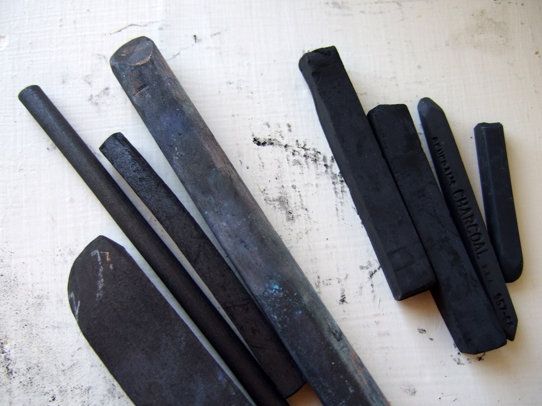 Vine and compressed charcoal sticks arranged on a light background