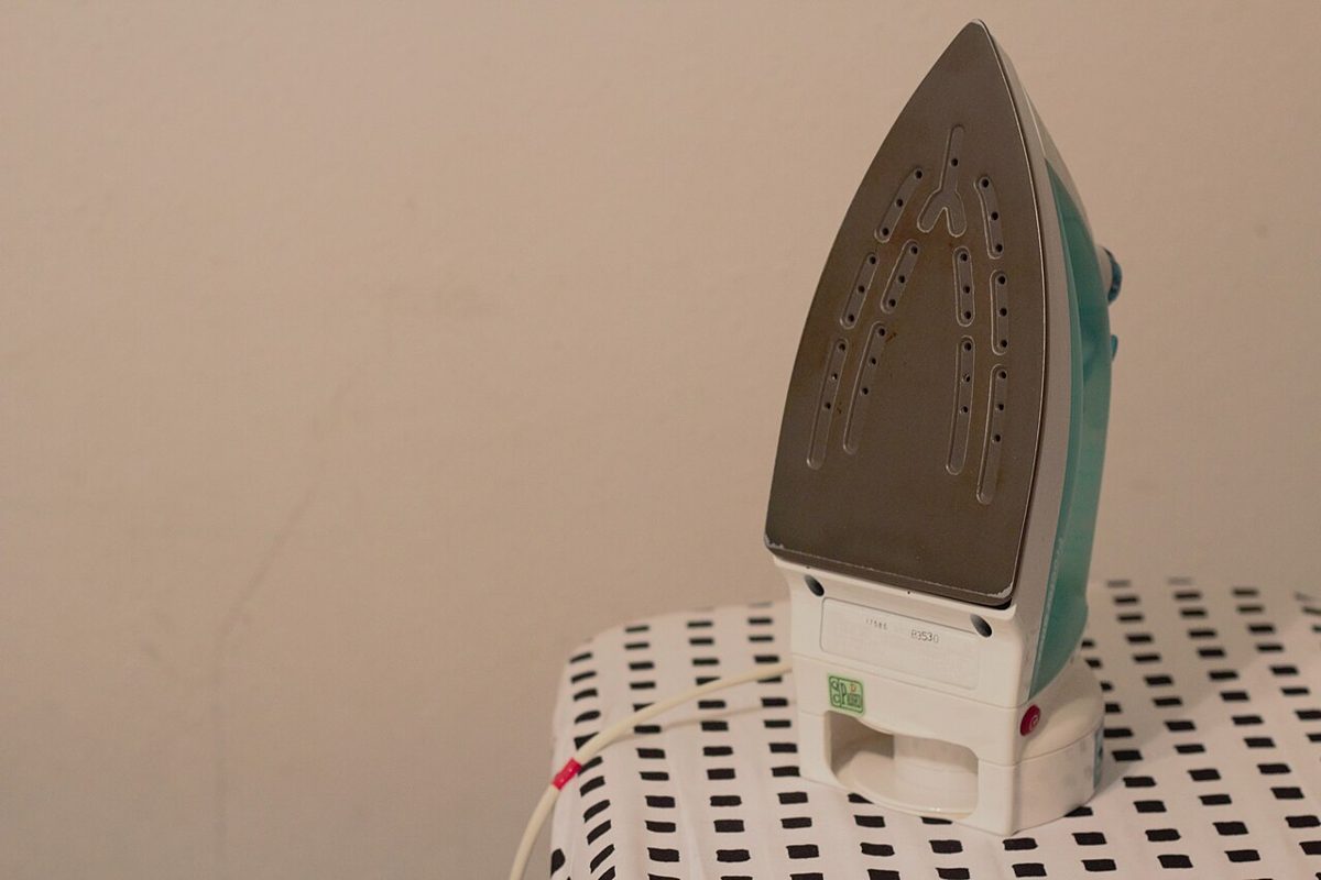 A clothes iron standing on an ironing board, illustrating garment finishing rather than a Polish cleaning service