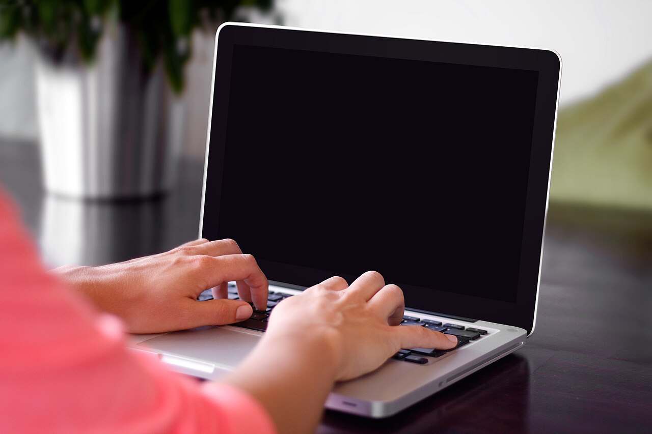 Hands typing on a laptop