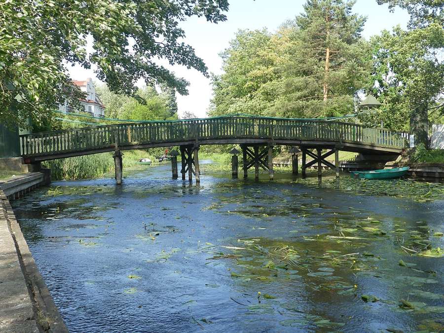 A wooden footbridge over a river flowing into Lake Ełk