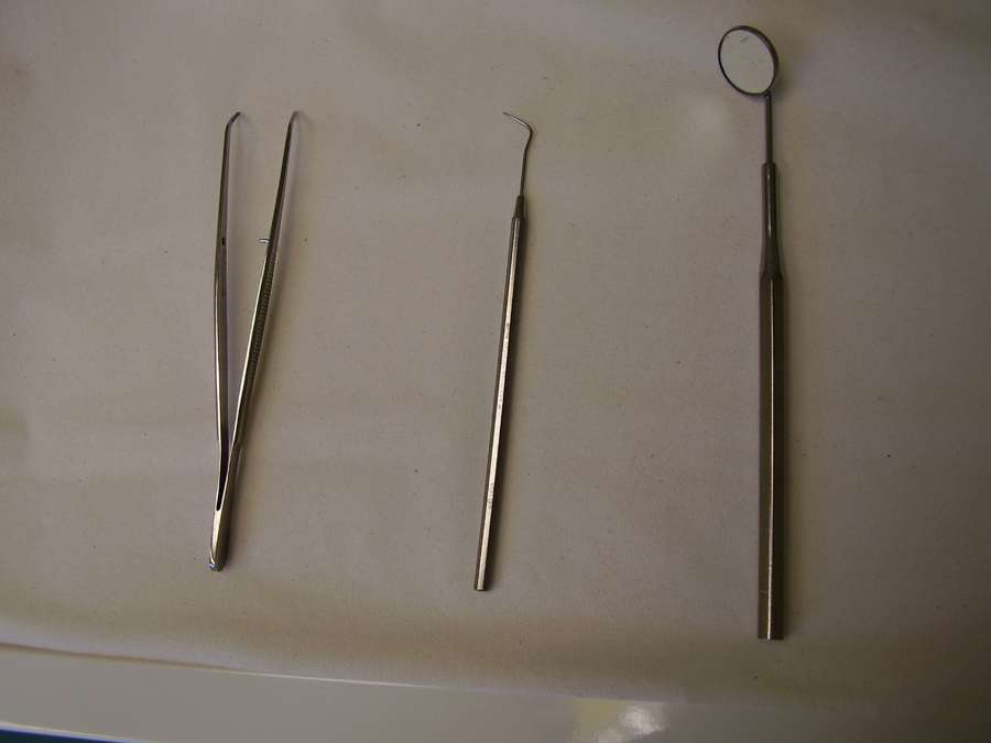 Dental tweezers, probe and mouth mirror on a clinic tray