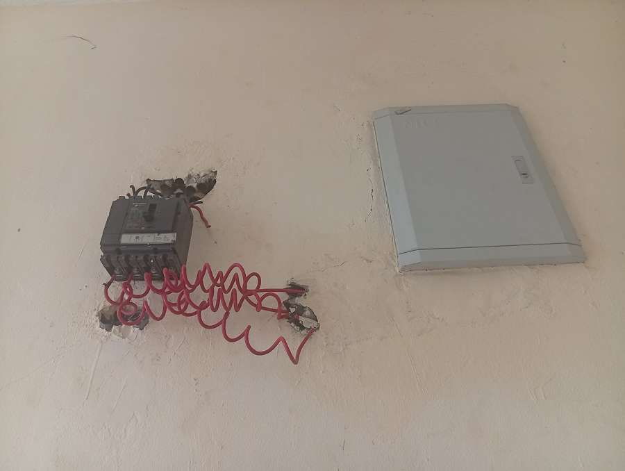 Exposed electrical wiring and a breaker box in a wall being renovated