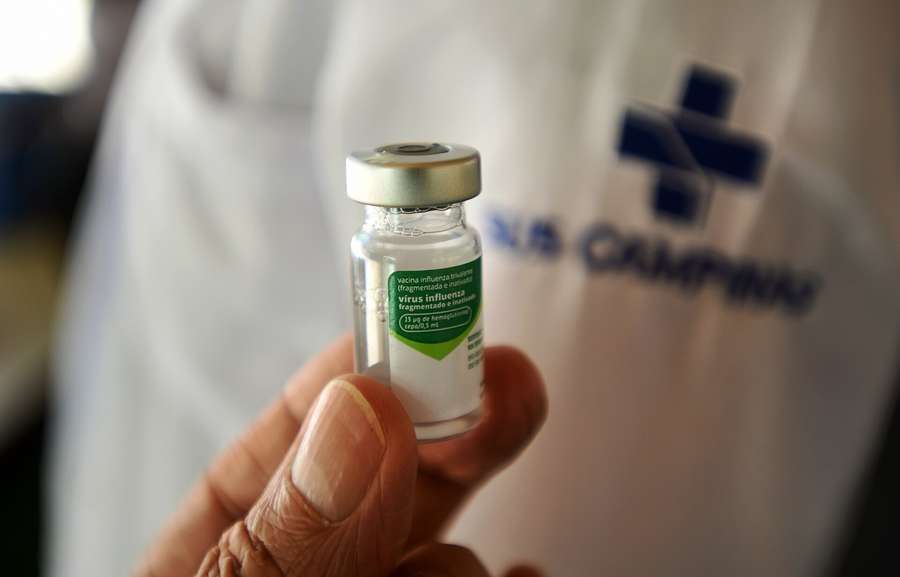 A flu vaccine vial held by a health worker