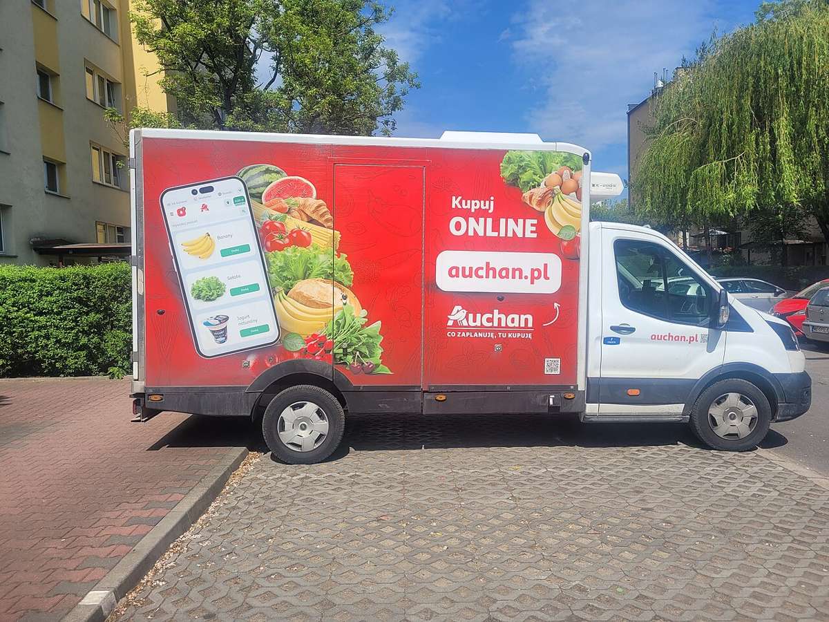 A white Auchan delivery van with a Kupuj online sign parked in Warsaw