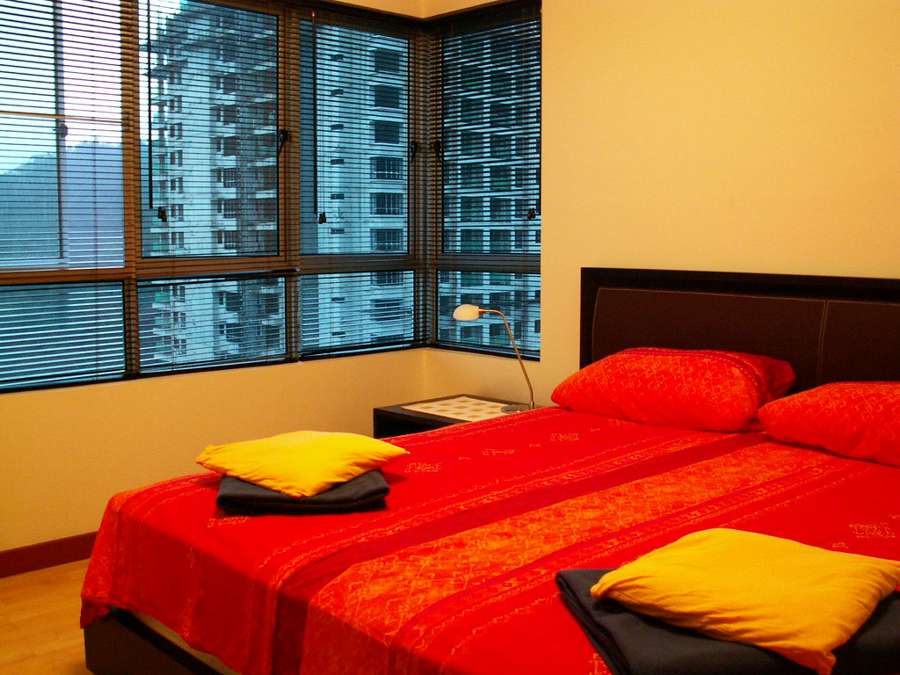 A furnished bedroom in a city apartment with a large window