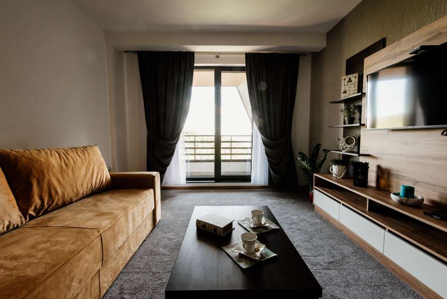 A furnished living room with a sofa, coffee table and television wall