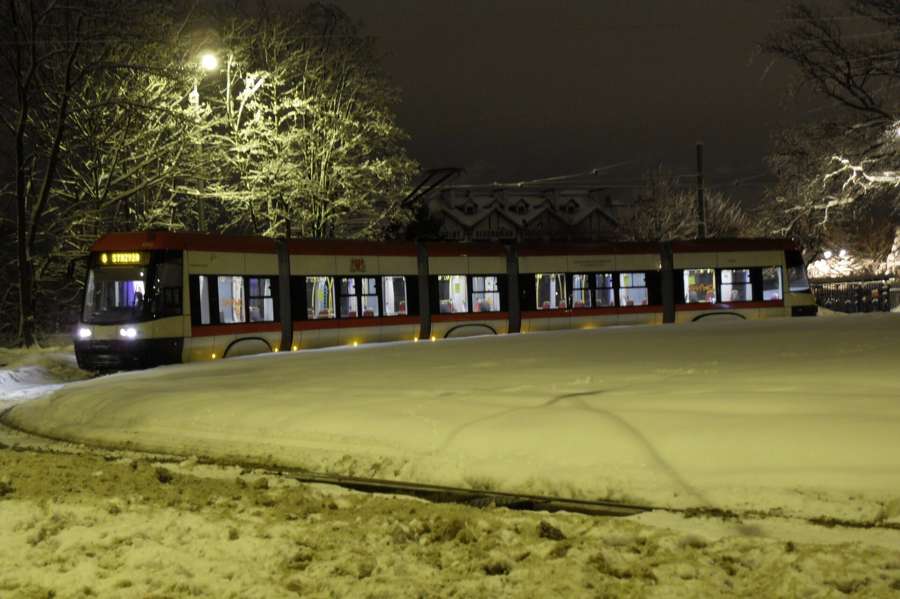A PESA tram running through snow at night in Gdansk