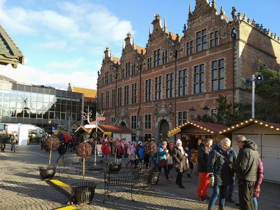 Christmas market stalls on Targ Węglowy in Gdańsk with the illuminated historic tenements of the Main Town behind