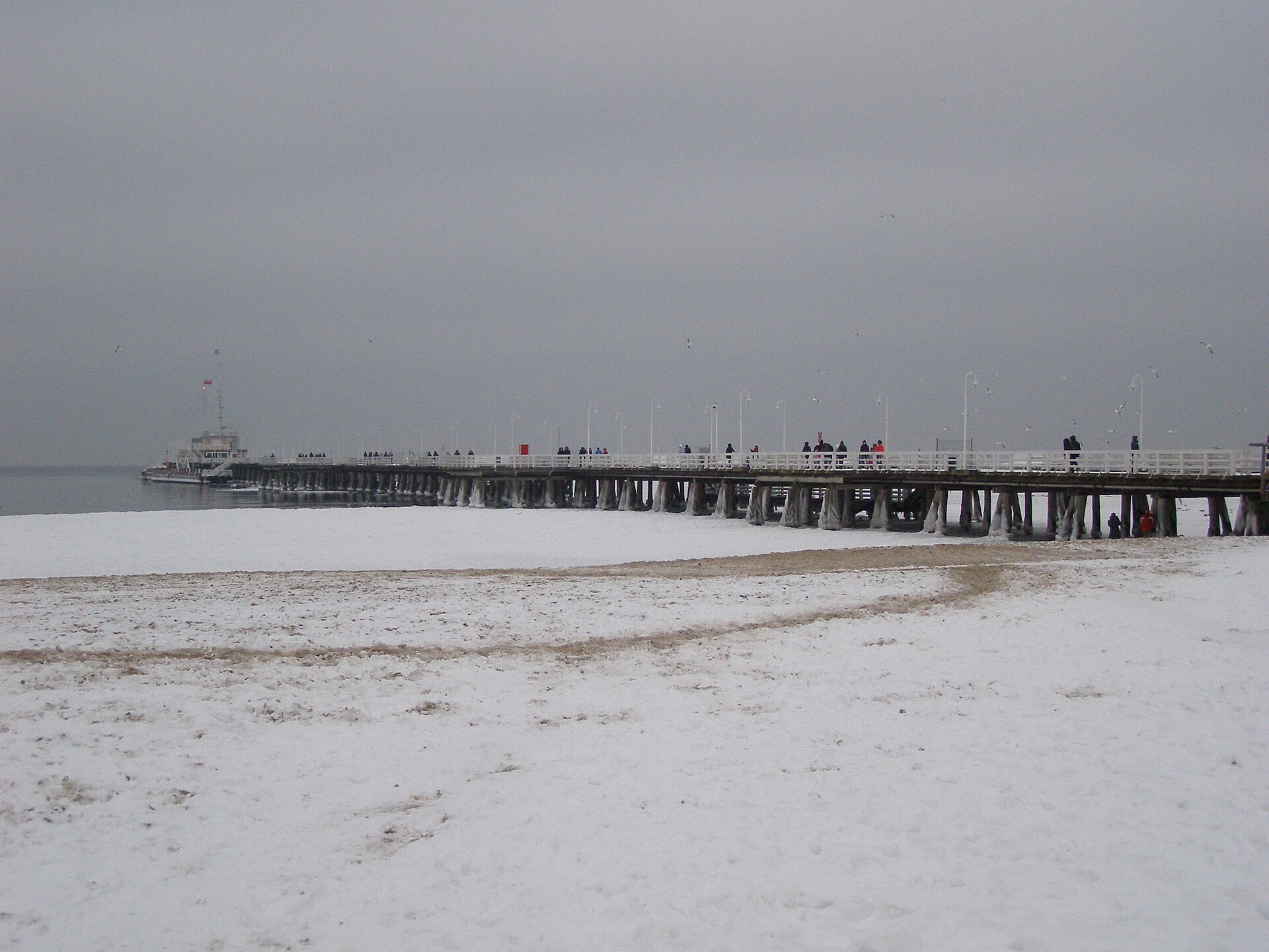 The wooden Sopot pier stretching over a snow-covered beach under a grey winter sky