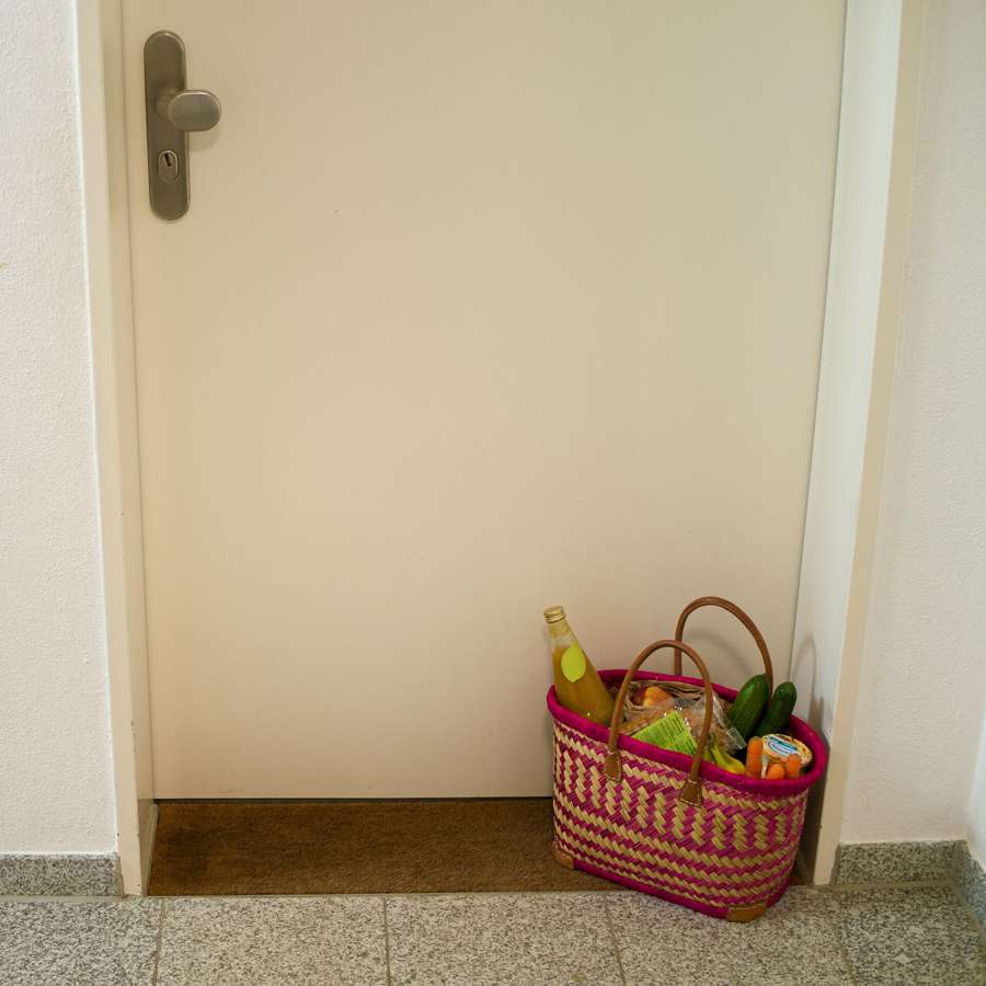 A basket of delivered groceries waiting at an apartment door