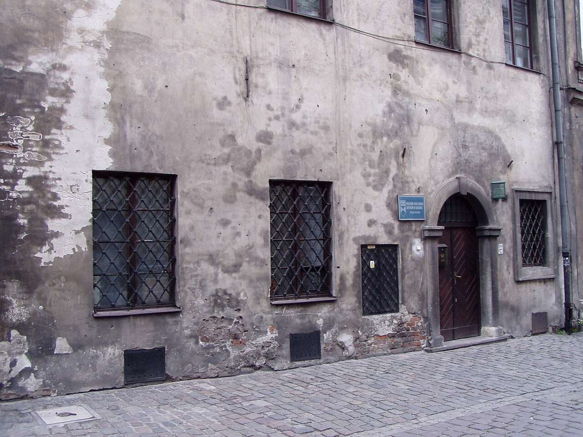 Old tenement facade with barred windows and a historic doorway in Kraków