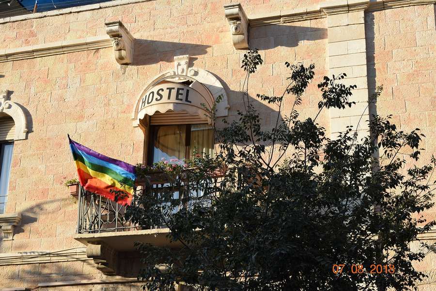 A rainbow pride flag hanging from a hostel balcony