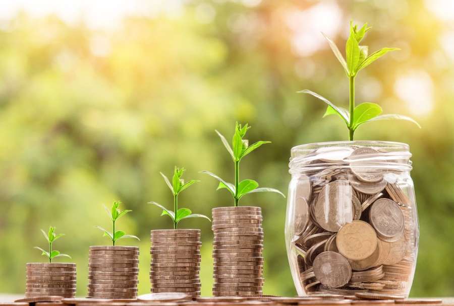Coins stacked in rising columns beside a small jar, symbolizing retirement savings growth