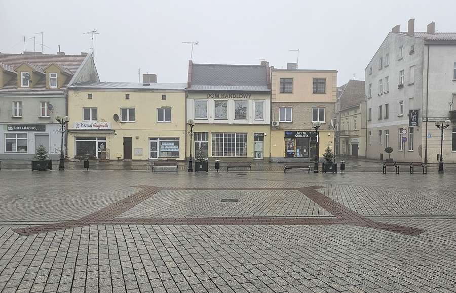 Market square in Inowrocław with historic townhouses on a foggy morning