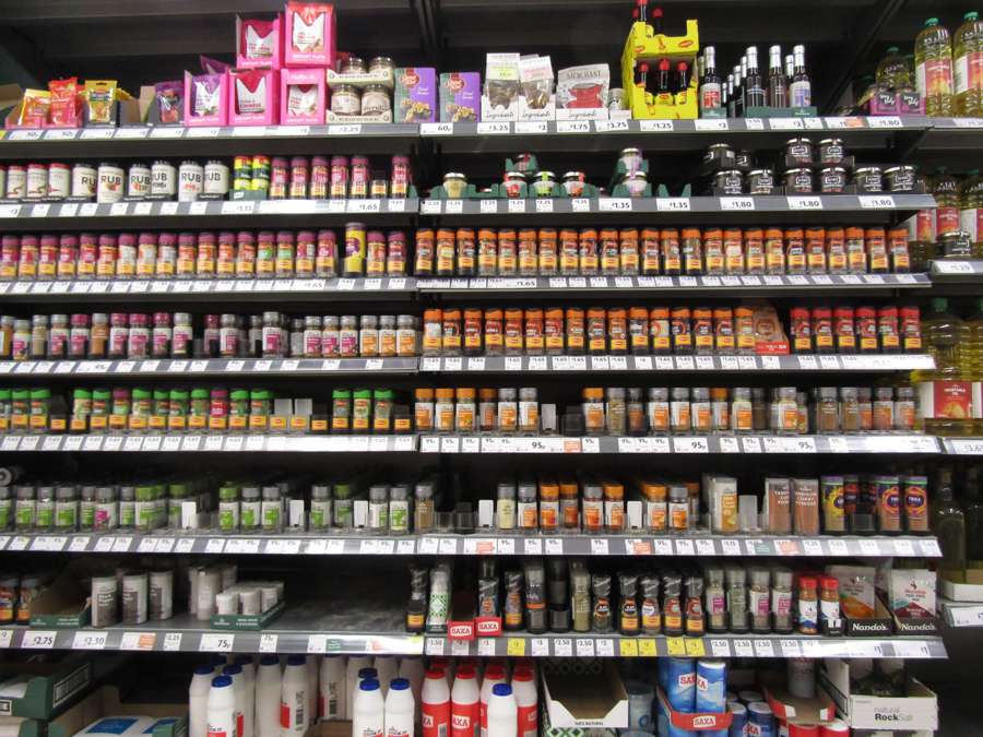 Supermarket shelves stocked with jars of herbs, spices and condiments