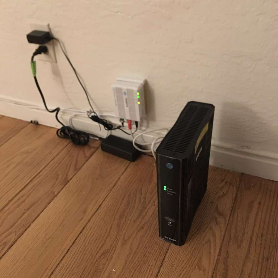 A home Wi-Fi router and fiber terminal on a wooden floor