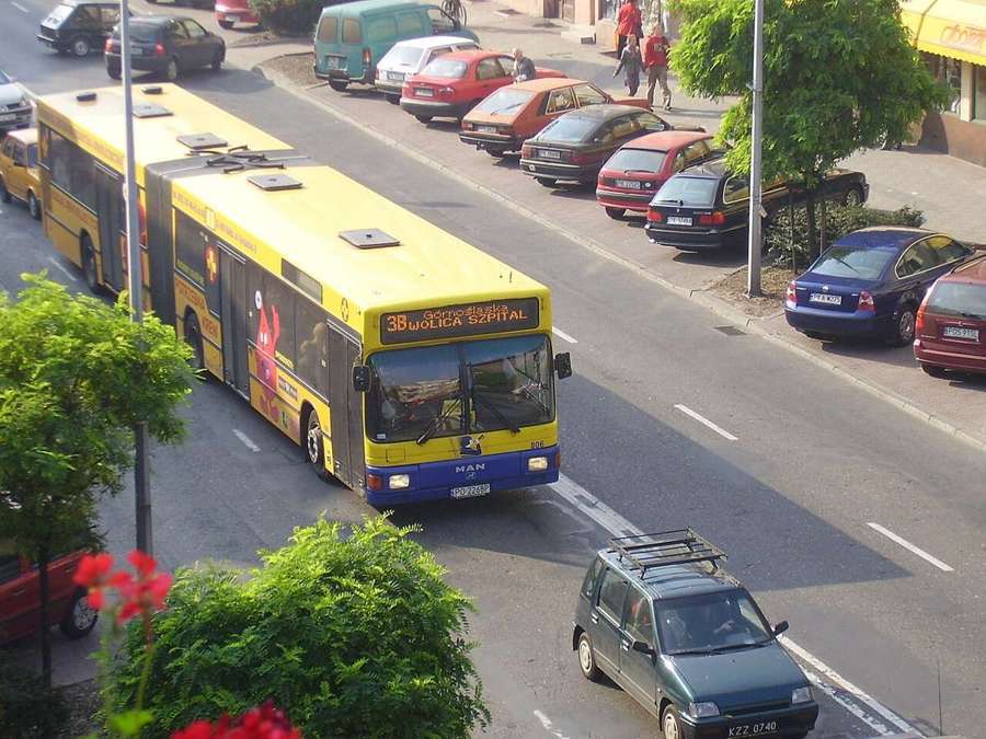 Yellow and blue articulated MZK bus in Kalisz on a street with parked cars