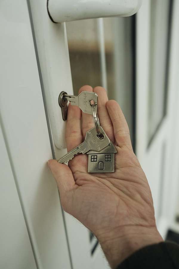 Keys with a house-shaped keyring going into a flat door lock