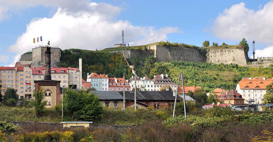 The Kłodzko fortress and the old town seen from below, with colourful houses at the foot of the hill