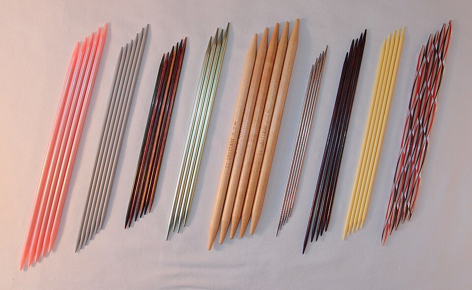 Sets of double-pointed knitting needles in different colours, materials and sizes laid side by side