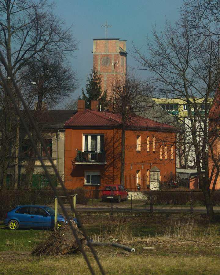 A red brick building and a tall brick water tower in Kutno among trees