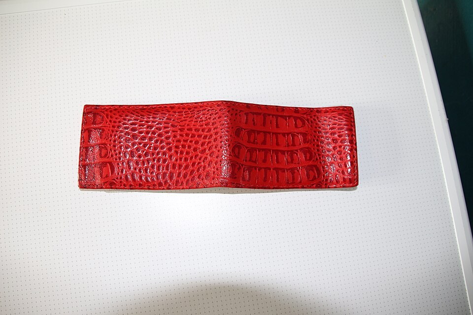 An open red leather cardholder with a textured surface on a pale background