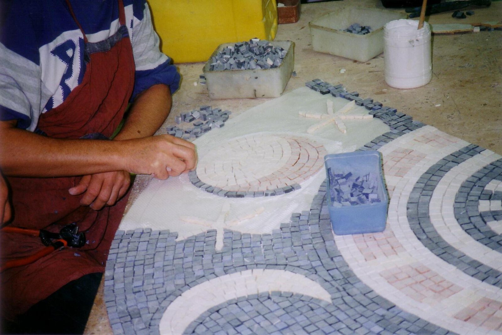 A person arranging pale and grey mosaic pieces on a worktable in Israel in February 2005