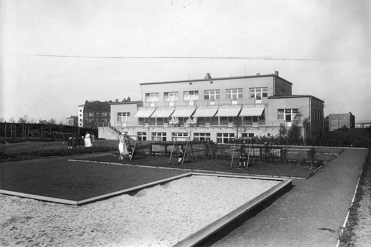 Historic photograph of a municipal nursery building in Katowice with a sandpit and swings