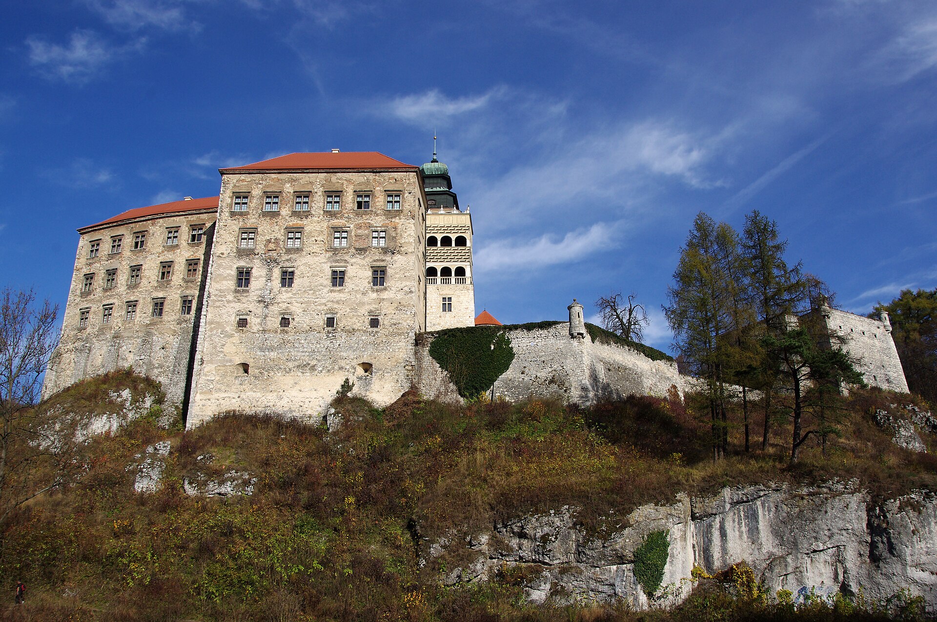 Pieskowa Skała castle on its limestone rock above autumn trees