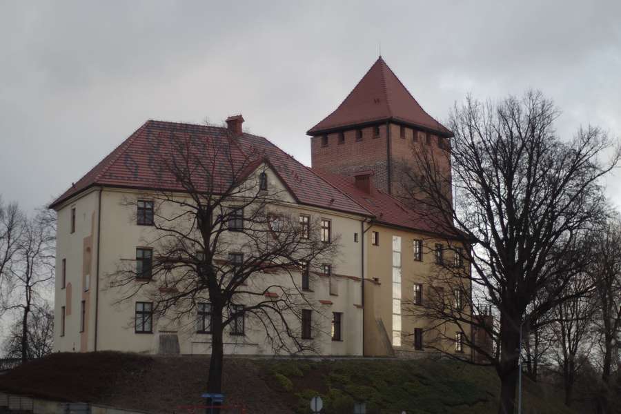 Oświęcim Castle with its red-roofed defensive tower above the river