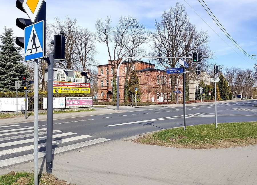 A crossing at Św. Jana and Partyzancka streets in Pabianice with a red brick building in the background