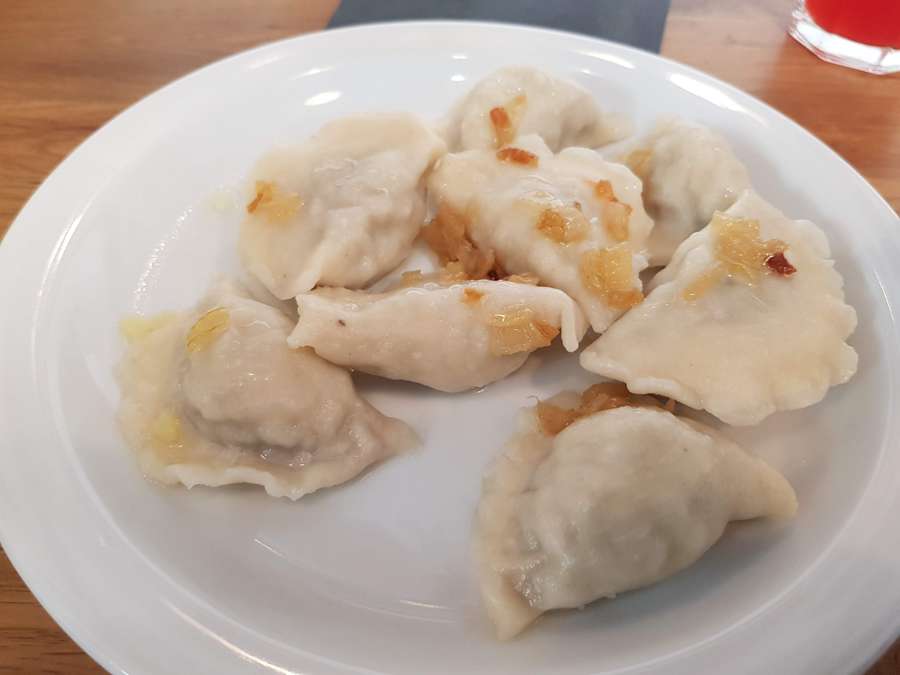 A plate of pierogi ruskie topped with fried onion