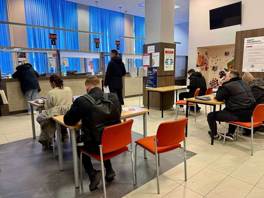 Visitors at tables in a Warsaw tax office customer hall