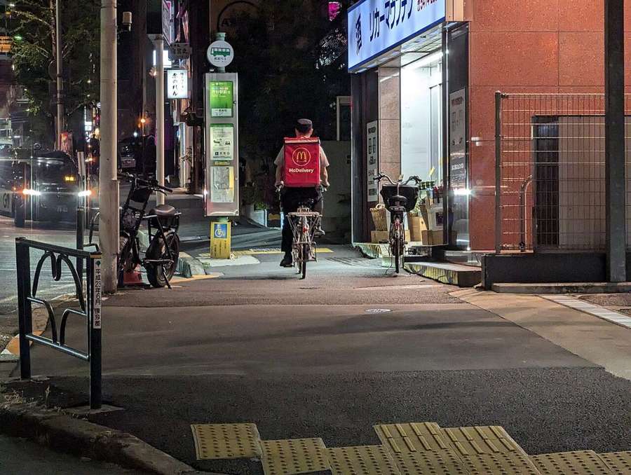A delivery rider cycling at night with a red insulated bag
