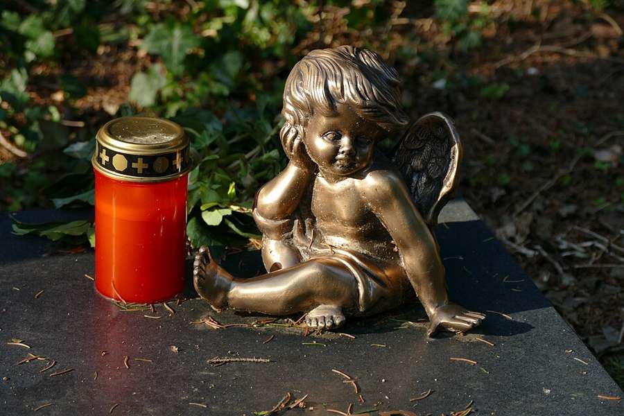 A grave candle and an angel figurine on a grave