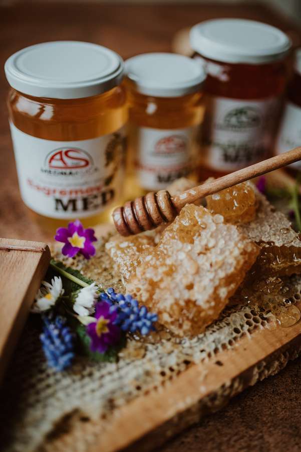 Jars of Polish honey with a piece of honeycomb and a wooden dipper