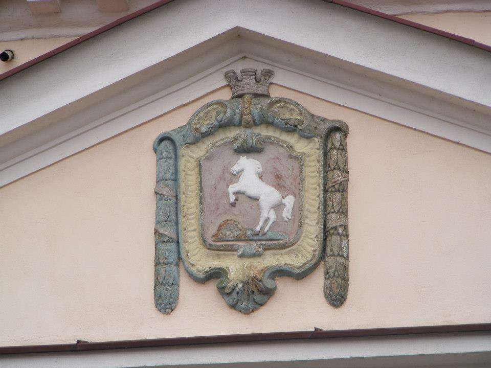 Coat of arms with a rearing white horse on a building facade in Konin