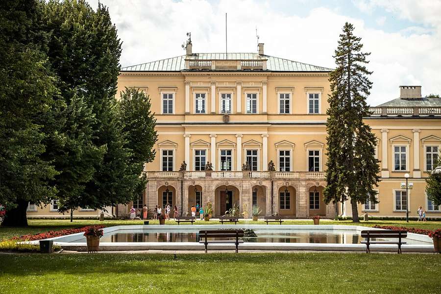 The yellow Czartoryski palace in Puławy with a pool and green lawn in front