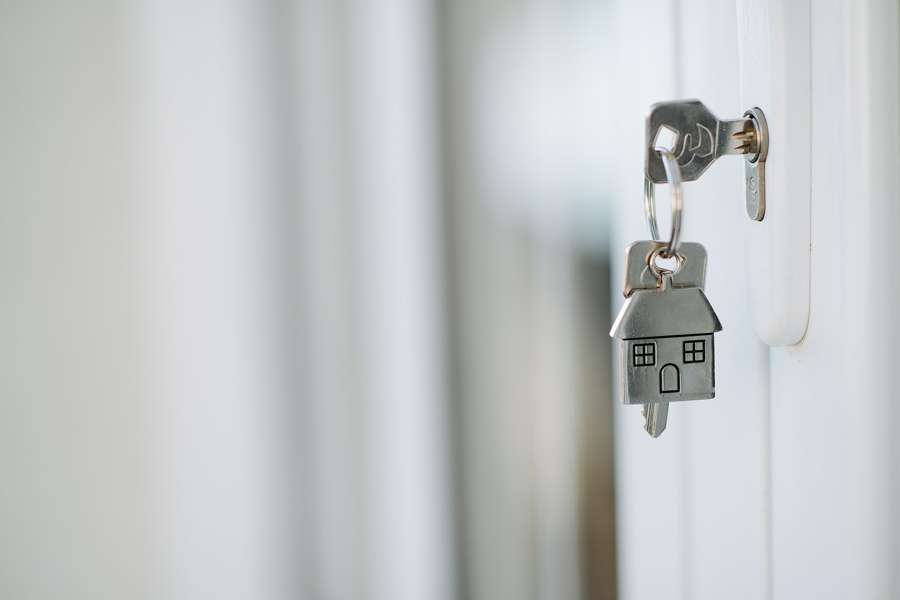 A key with a house-shaped keychain in a door lock - never pay for a flat you have not verified