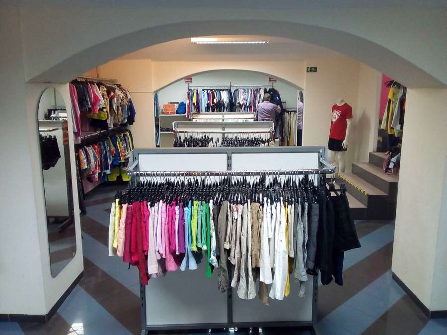 Colour-sorted clothing racks inside a second-hand shop